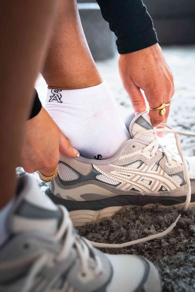 Witte Sockly Classic sok tijdens het aantrekken van een schoen